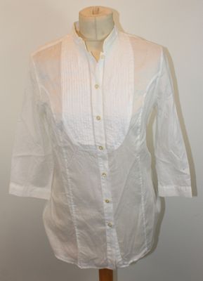 La chemise est blanche et possède un col boutonné.