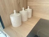 three white canisters sitting on a shelf in a kitchen