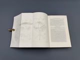 un livre ouvert posé sur une table, à côté d'une horloge