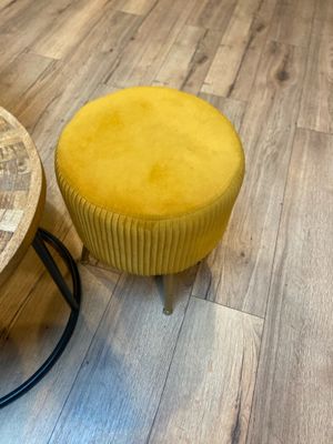 un tabouret jaune et une table ronde posés sur un parquet