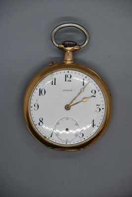 un gros plan d'une montre de poche en or posée sur une surface grise