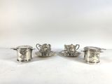 three silverplated cups and saucers on a white surface