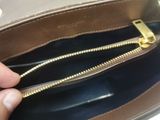 a person holding a brown purse with a gold zipper