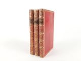 two old books sitting on top of each other on a white surface