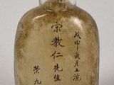 a glass bottle with writing on it on a white surface