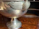a silver bowl with a bird on it sitting on a table
