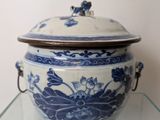 a blue and white bowl with a lid on a glass shelf