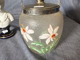 a glass vase with flowers painted on it next to a figurine