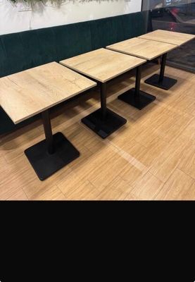 trois tables en bois posées sur un parquet, à côté d'un mur vert