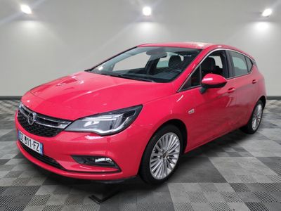 Une Opel rouge est garée dans une pièce au sol carrelé en damier.