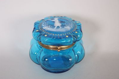 un bocal en verre bleu avec un couvercle doré, posé sur une table blanche