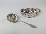 une cuillère en argent et un bol en argent posés sur une table blanche