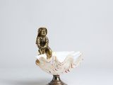 statue of a monkey sitting on a shell on a white background