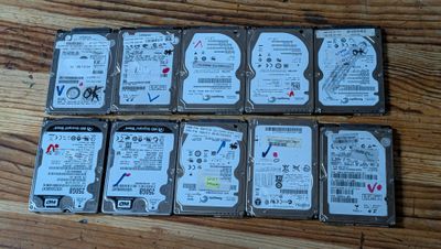Plusieurs disques durs sont alignés sur une surface en bois