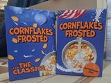 two boxes of cornflakes frosted cereal sitting on a table