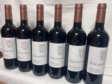 six bouteilles de vin sont alignées sur une table