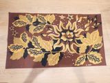un tapis marron orné de feuilles dorées, posé sur un parquet