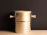 a silver ice bucket sitting on a table next to a black wall