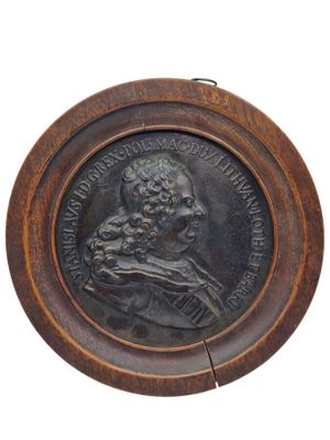 un vieux médaillon en bronze représentant un homme tenant un chien, sur fond blanc