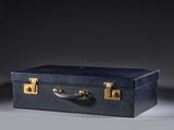 navy blue leather suitcase with brass handles on a grey background