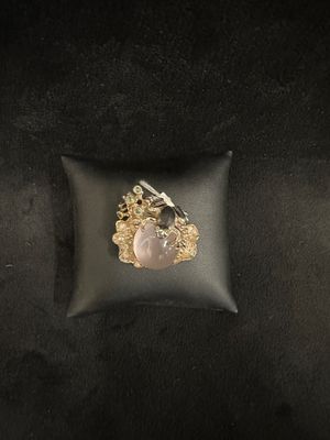 an image of a gold and pink stone ring on a black pillow