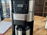 the coffee maker is sitting on a wooden table in a coffee shop