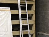 une échelle appuyée contre un mur, à côté d'une pile de palettes