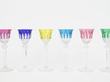 six colorful wine glasses lined up in a row on a white surface