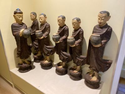 many statues of monks on a shelf in a room
