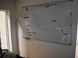 a white board on the wall in the corner of a room