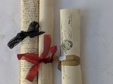 two rolled up papers with a red ribbon tied to them