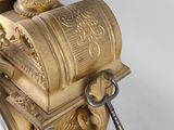 a gold clock with a key on top of it