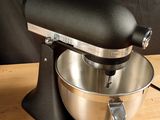 a black mixer on a wooden table with a black background