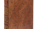 un vieux livre à la couverture brune posé sur une surface blanche
