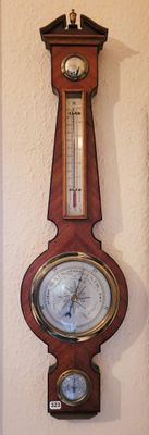 une horloge accrochée au mur, sur laquelle se trouve un baromètre