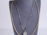 a close up of a necklace on a mannequin with a coin on it
