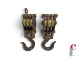 pair of antique cast iron pulleys with hooks on a white background