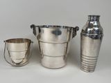 three silver vases and two cups on a white surface