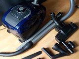 a blue and black vacuum sitting on a table next to other items