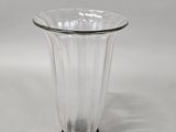 a clear glass vase with a black base on a white background