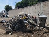 un tas d'ordures posé au milieu d'un terrain en terre battue, près d'un mur