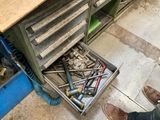 un tiroir rempli d'outils posé à même le sol d'un garage