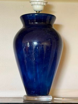 a blue vase sitting on a shelf next to a lamp