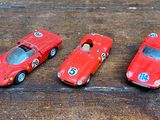 trois petites voitures rouges posées sur une table en bois