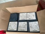 six batteries in a cardboard box on a table with a pair of scissors