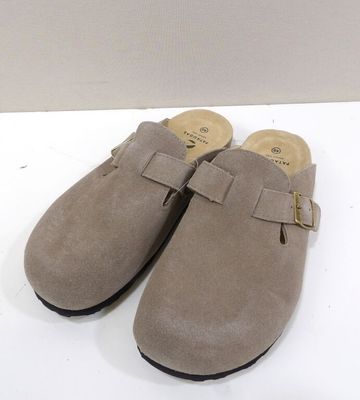 sabots en daim beige à semelles noires, posés sur un fond blanc