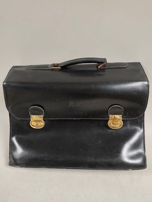 an old black briefcase sitting on top of a white table
