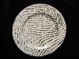 a white plate with black spots on it on a black background