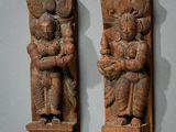 une paire de sculptures en bois représentant un homme et une femme tenant un enfant dans leurs bras