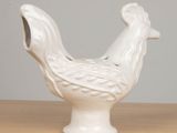 a white ceramic chicken sitting on a wooden table